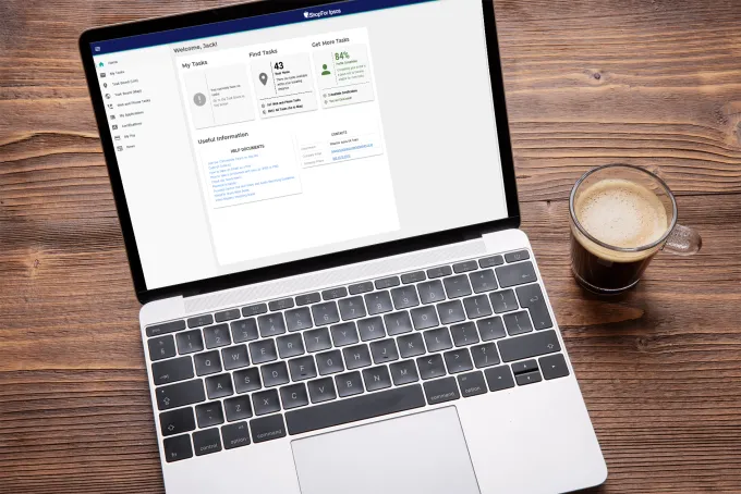 A laptop on a wooden table showcasing the iShopFor Ipsos site